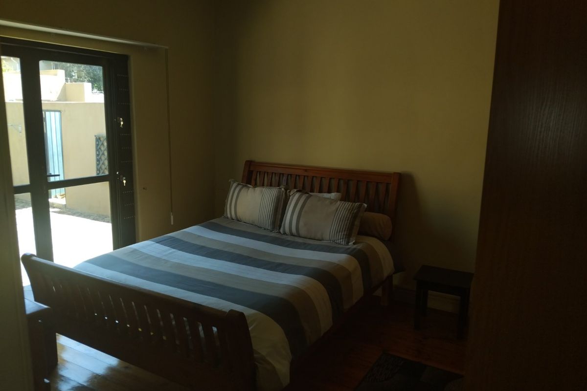 A bedroom featuring hardwood flooring and a glass sliding door providing access to an outdoor area.