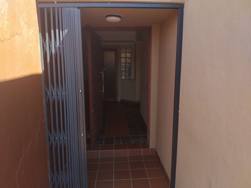 Entrance area featuring tiled flooring, a security gate, and a glass block window providing natural light into the hallway.