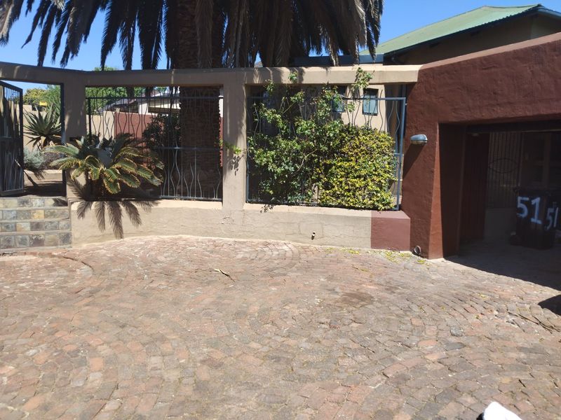 Front entrance area featuring a circular brick paved driveway, boundary wall with wrought iron inserts, and stone-tiled steps leading to the property entrance.