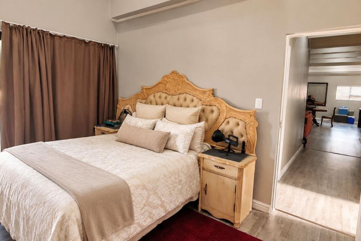 A bedroom featuring laminate flooring and a sliding glass door providing access to an outdoor area, with a doorway leading to an adjacent room.