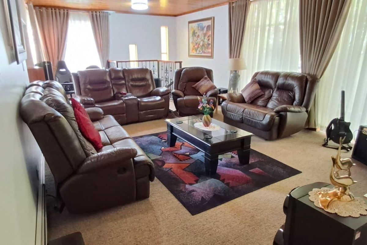 Spacious living room featuring a timber ceiling and an open staircase railing, providing a comfortable and functional family area.