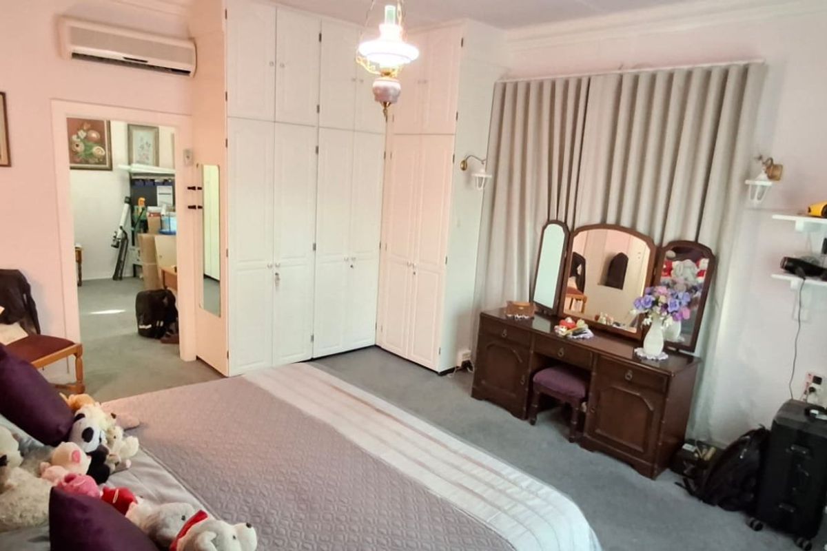 A spacious bedroom featuring extensive built-in cabinetry, a wall-mounted air conditioning unit, and neutral carpeting, offering a functional and well-organized living space.
