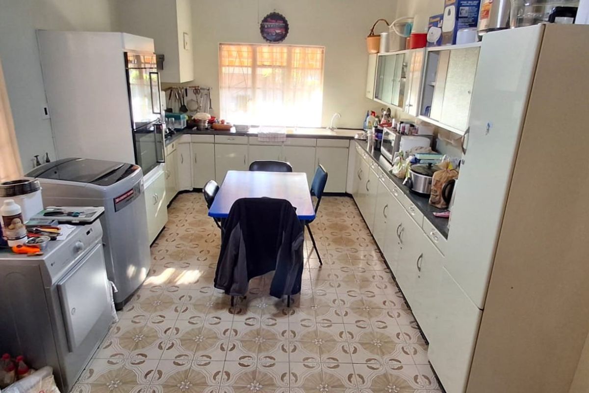 A functional kitchen featuring extensive built-in cabinetry, laminate countertops, a double sink, and tiled flooring, offering a practical layout with potential for modernization.
