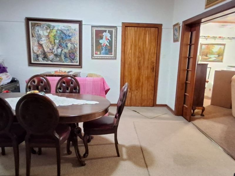 A dining room featuring a wooden door and carpet flooring, with an open transition into an adjacent living area.
