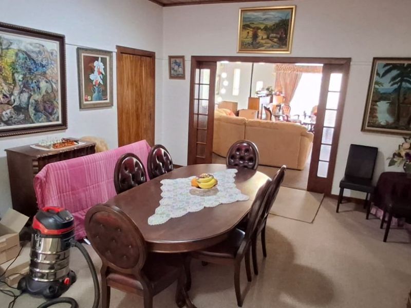 A traditional dining room featuring timber door frames and glass-panelled sliding doors leading into an adjacent living area.