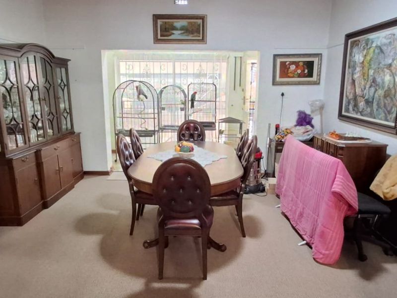 A traditional dining room featuring carpeted flooring and a secure access point leading to the exterior.