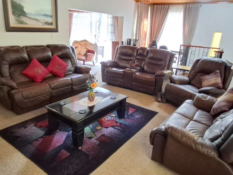 A spacious living room featuring carpeted flooring, wrought iron staircase detailing, and recessed wall niches, providing a comfortable and functional family area.