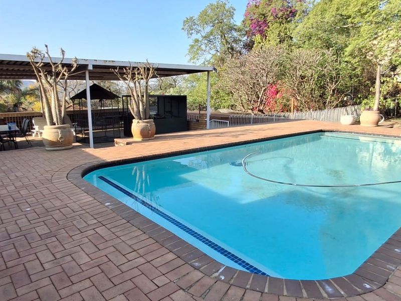 Outdoor pool area featuring a paved deck and a covered patio space, ideal for relaxation and entertaining.