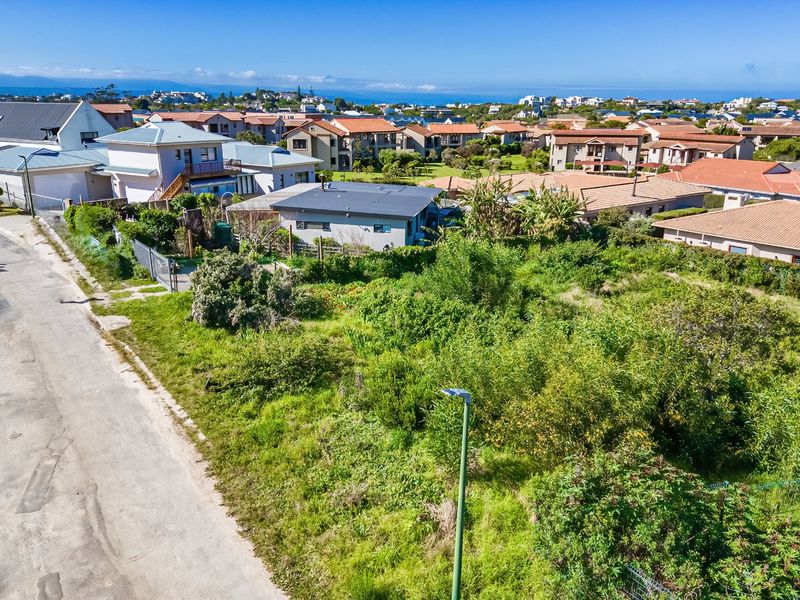 Aerial view of a vacant residential plot situated in a developed neighborhood with street access and surrounding residential properties.