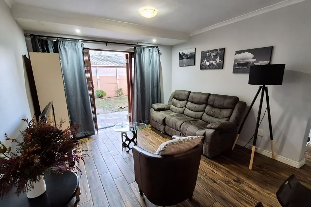 A comfortable living room featuring wood-look tile flooring and a sliding glass door that provides direct access to the rear garden area.
