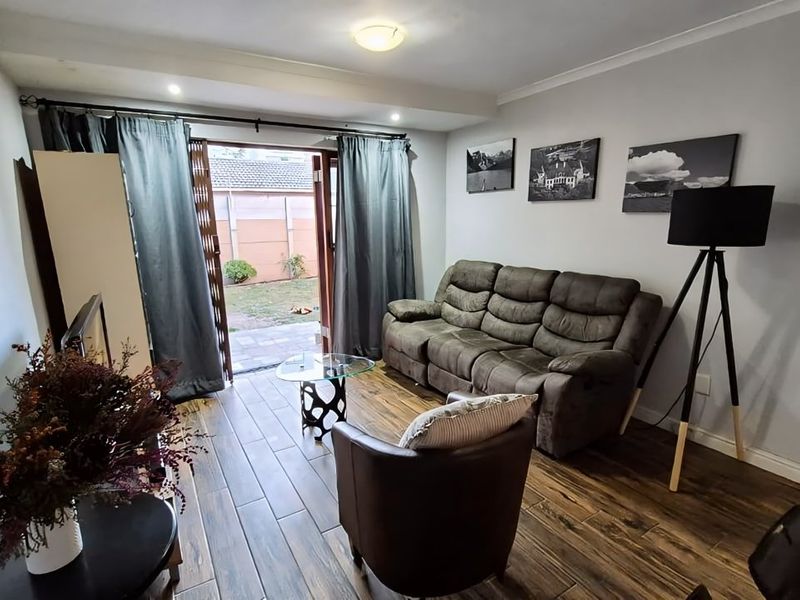 A comfortable living room featuring wood-look tile flooring and a sliding glass door that provides direct access to the rear garden area.