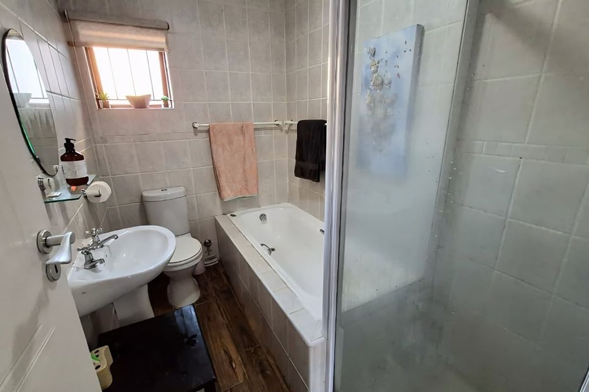 A functional bathroom featuring a pedestal basin, toilet, built-in bathtub, and a separate shower enclosure with tiled finishes throughout.