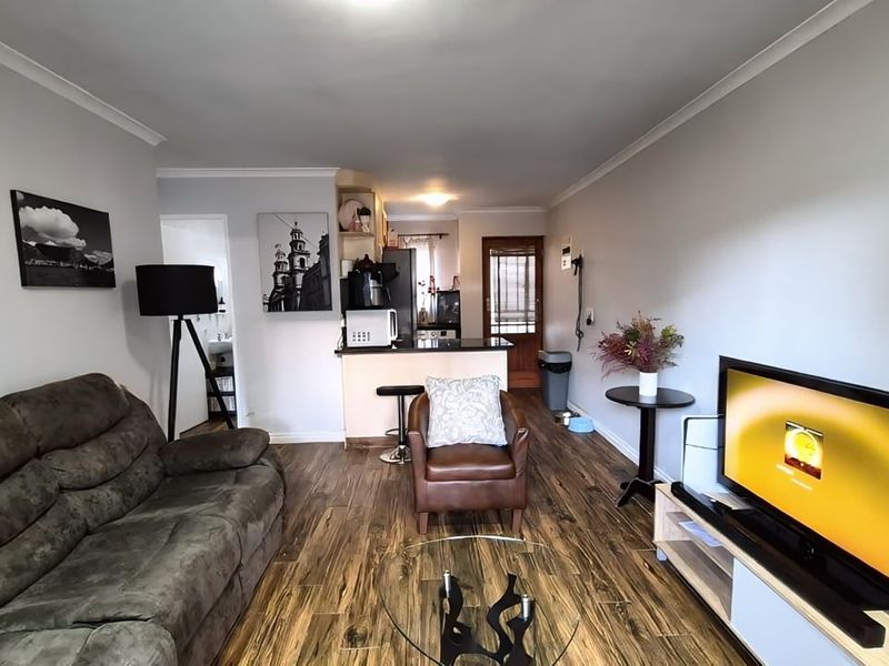Open plan living area featuring laminate flooring and a breakfast counter connecting to the kitchen space.