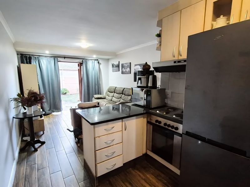 Open-plan kitchen and living area featuring tiled flooring, built-in cabinetry with granite countertops, and direct access to an outdoor patio area.