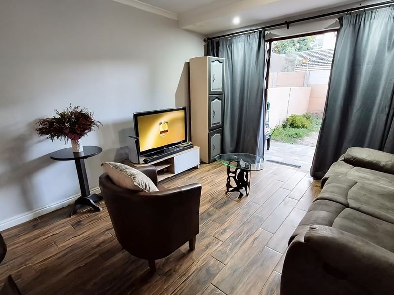 A living room featuring wood-look tile flooring and a sliding glass door providing direct access to the outdoor area.