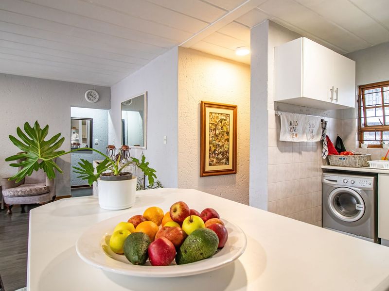 Open plan living area featuring a functional kitchen space with built-in cabinetry, tiled backsplash, and integrated laundry appliance connection.
