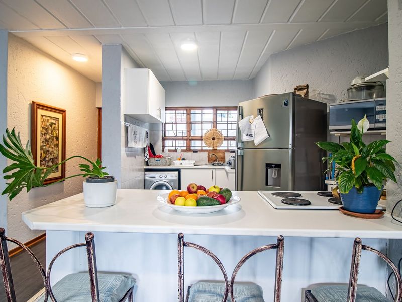 Open plan kitchen area featuring a breakfast bar, built-in cooktop, and integrated cabinetry, creating a functional and connected living space.