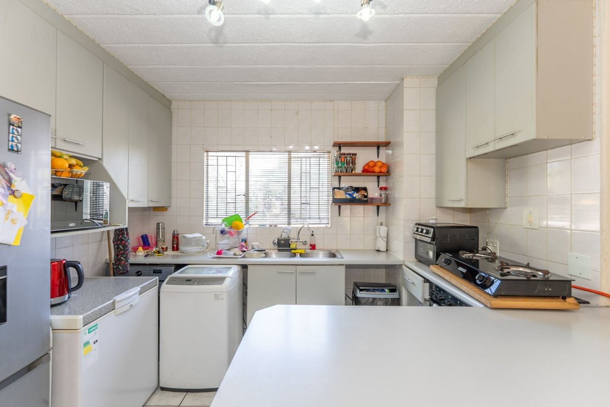 A functional kitchen featuring built-in cabinetry, a double sink, tiled backsplash, and ample counter space with integrated lighting.