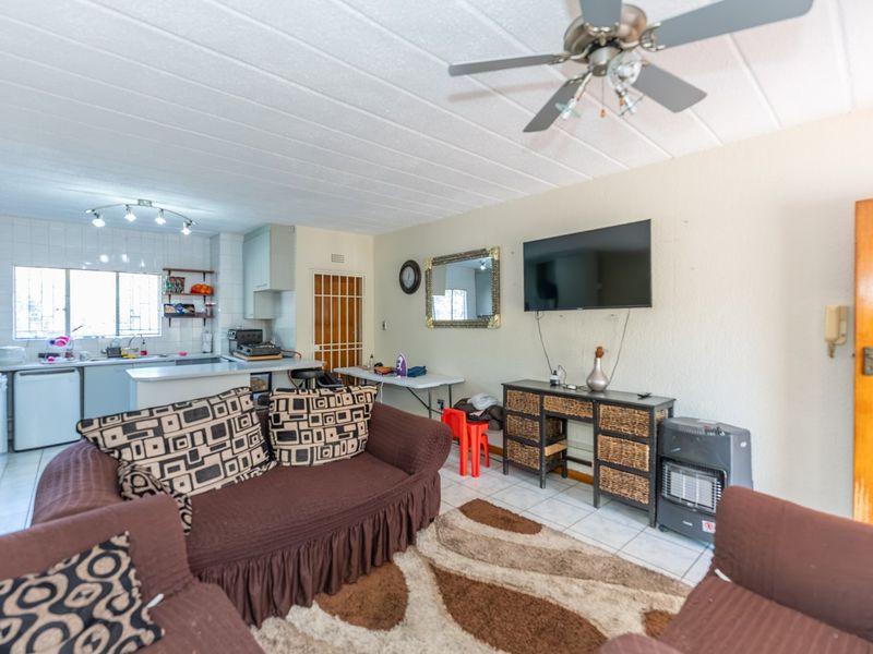Open-plan living area featuring a combined kitchen with tiled flooring, ceiling fan, and direct access to the living space.