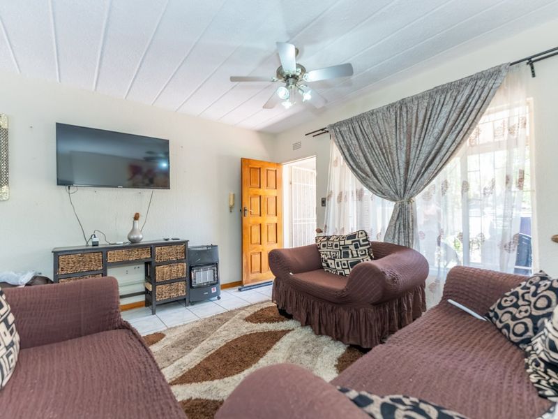 A living room featuring tiled flooring, a ceiling fan, and a textured ceiling, with direct access to the exterior through a timber door.