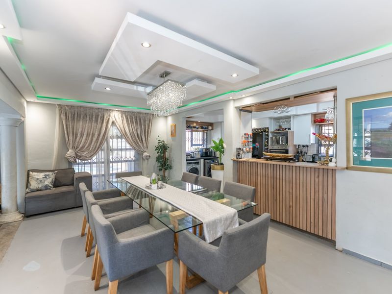 Open-plan dining area featuring a modern recessed ceiling with ambient lighting, a breakfast bar, and seamless flow into the adjacent kitchen space.