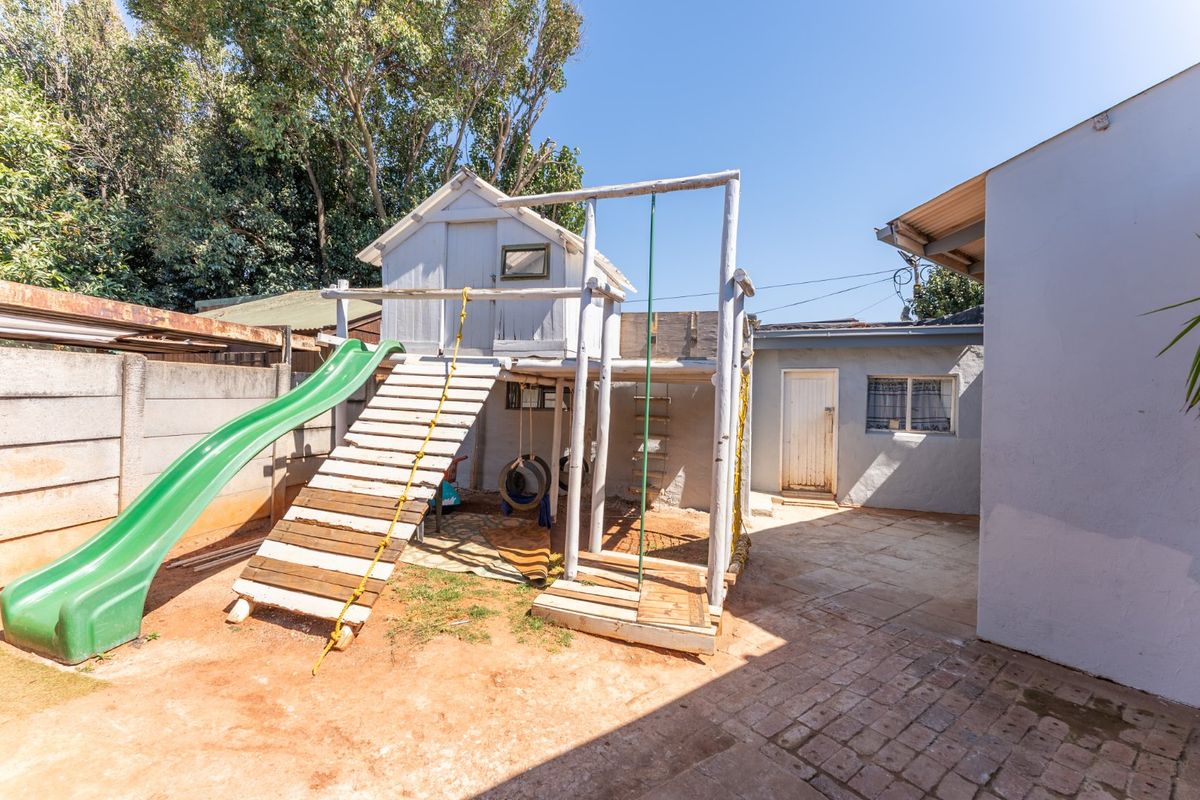 Rear courtyard area featuring paved flooring, a concrete boundary wall, and access to the main building structure.