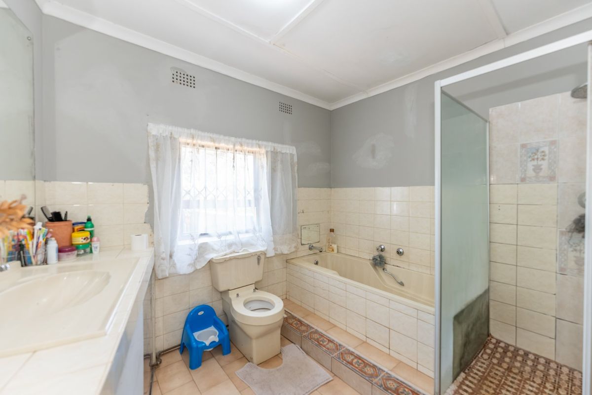A dated bathroom featuring a built-in vanity, bathtub, and separate shower enclosure, requiring cosmetic updates to modernize the space.
