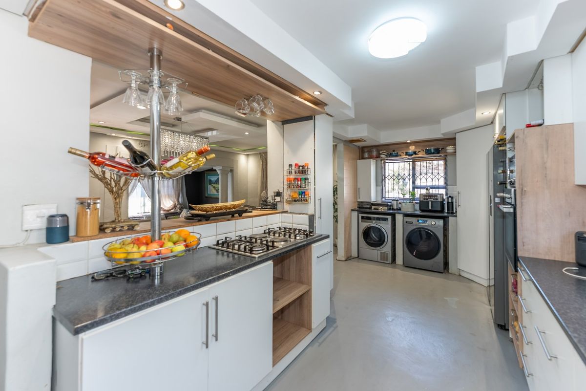 Modern kitchen featuring a gas hob, ample built-in cabinetry, laminate countertops, and integrated laundry facilities with a functional layout.