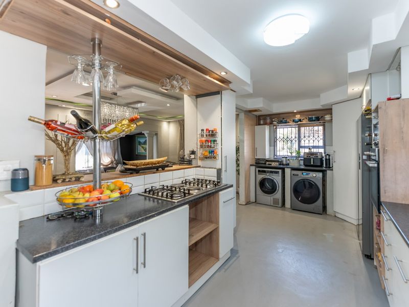 Modern kitchen featuring a gas hob, ample built-in cabinetry, laminate countertops, and integrated laundry facilities with a functional layout.