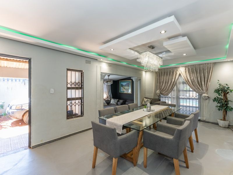 Spacious dining area featuring a modern recessed ceiling with integrated LED lighting, a crystal chandelier, and direct access to the exterior.