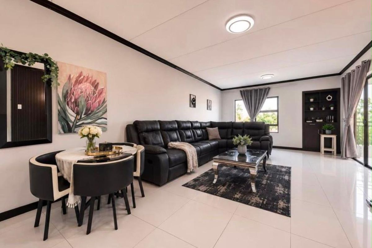 Spacious open-plan living and dining area featuring polished tile flooring, modern recessed lighting, and a built-in shelving unit with access to a balcony.
