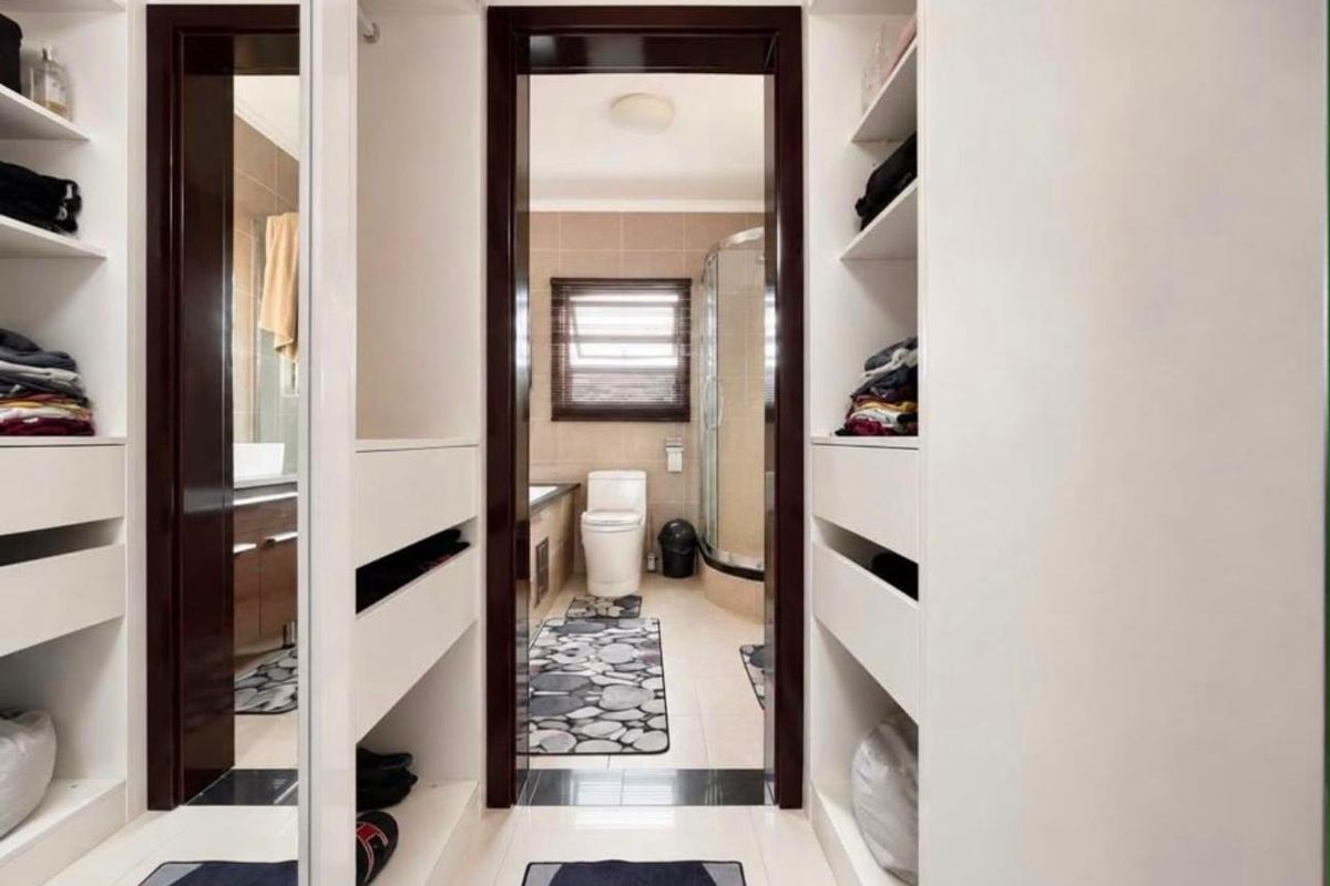 A well-organized dressing area leading into a bathroom featuring a shower enclosure, bathtub, toilet, and vanity with built-in storage cabinetry.