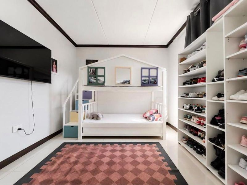 A well-maintained bedroom featuring tiled flooring, crown molding, and extensive built-in shelving for storage.