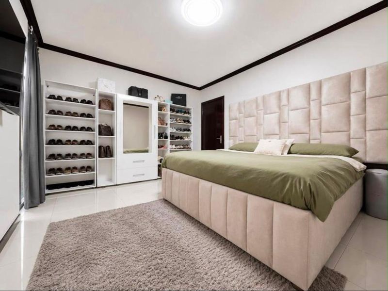 A well-maintained bedroom featuring tiled flooring, a built-in wardrobe unit, and a modern ceiling light fixture.