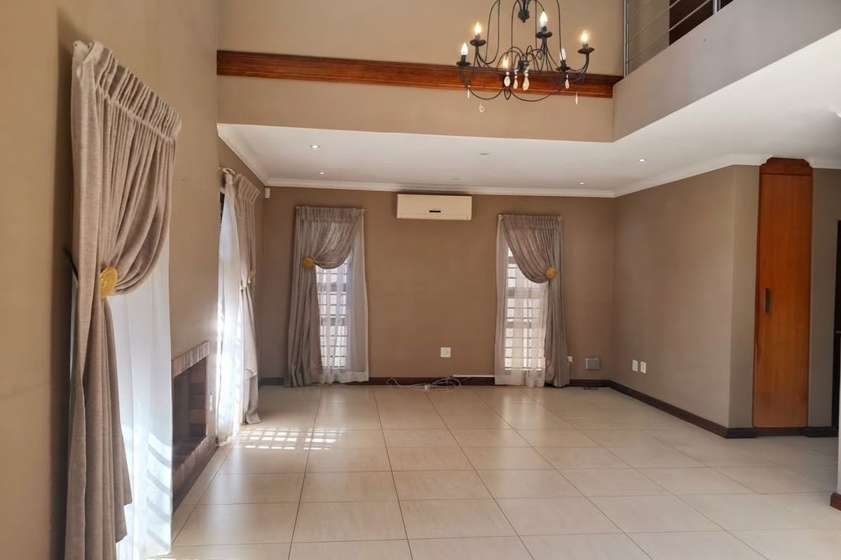 Spacious open-plan living area featuring tiled floors, a built-in fireplace, air conditioning, and a mezzanine level with a decorative chandelier.