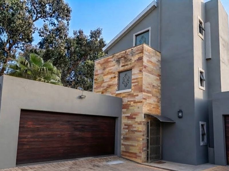 Modern townhouse exterior featuring a double garage, stone-clad facade, and secure entrance with paved driveway.