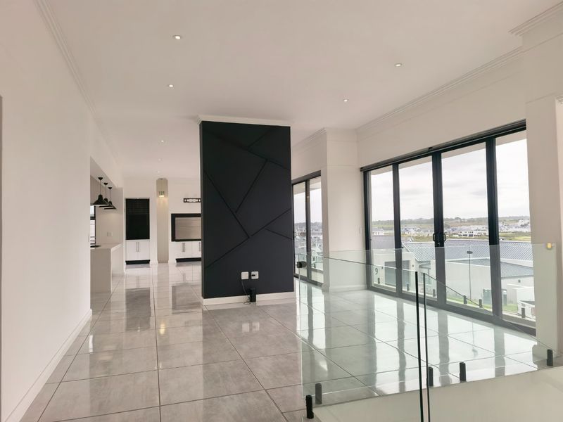 Spacious open-plan living area featuring modern porcelain tiles, a striking decorative feature wall, and large glass sliding doors offering abundant natural light.