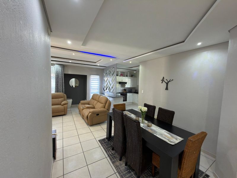 Open-plan living and dining area featuring tiled floors, recessed ceiling lighting, and a modern kitchen with built-in cabinetry and appliances.