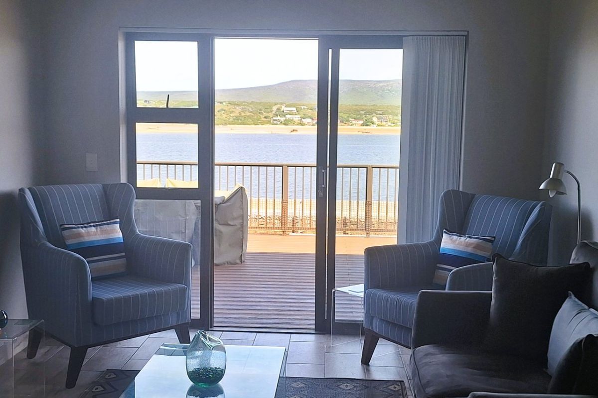 A comfortable living room featuring tiled floors and large sliding glass doors that open onto a balcony with scenic water views.