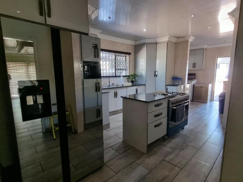 Modern kitchen featuring built-in cabinetry, a central island with a gas stove, tiled flooring, and ample storage space.