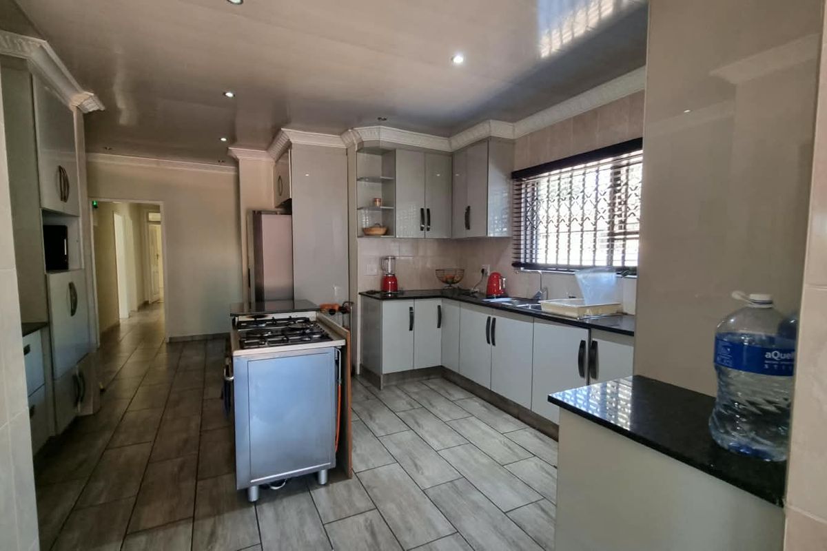 A functional kitchen featuring modern grey cabinetry, granite countertops, a gas stove, and tiled flooring with recessed lighting.