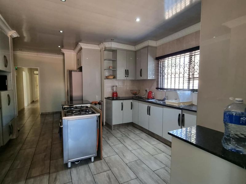 A functional kitchen featuring modern grey cabinetry, granite countertops, a gas stove, and tiled flooring with recessed lighting.