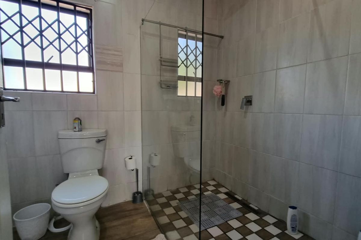 A functional bathroom featuring a walk-in shower with a glass screen, tiled walls, and a standard toilet.