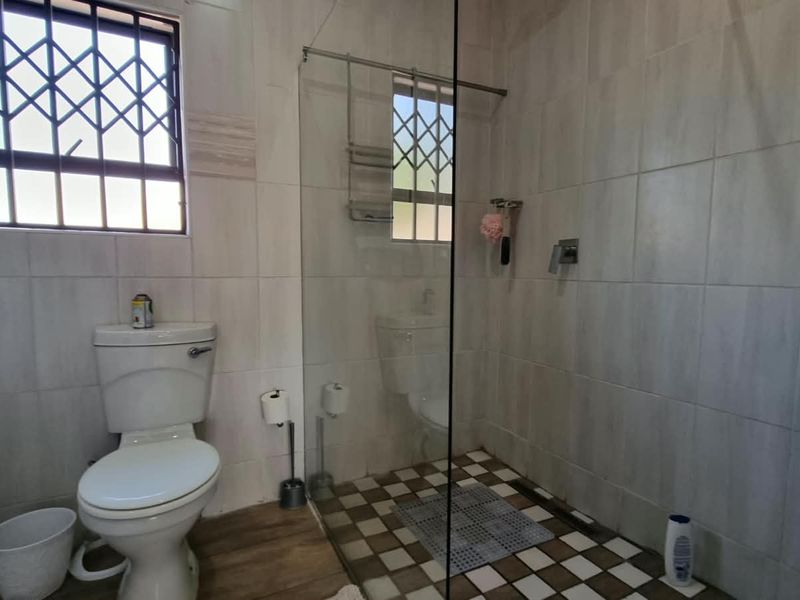 A functional bathroom featuring a walk-in shower with a glass screen, tiled walls, and a standard toilet.