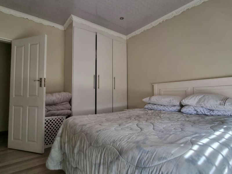 A functional bedroom featuring built-in wardrobes, crown molding, and laminate flooring, offering a neutral base for personalization.