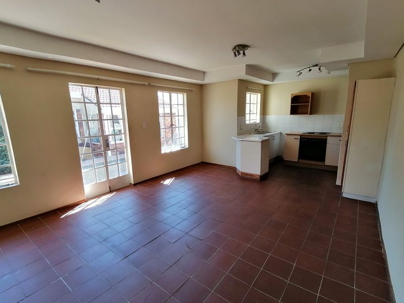 An open-plan living and kitchen area featuring tiled flooring, built-in cabinetry, and direct access to the exterior through french doors.