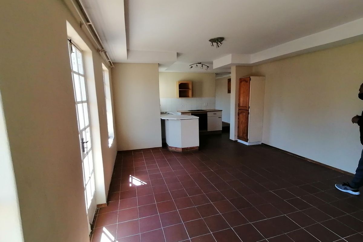 An open-plan living and kitchen area featuring tiled flooring, built-in cabinetry, and access to the exterior via french doors.