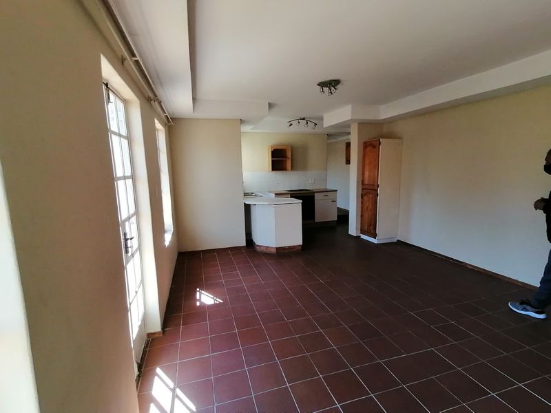 An open-plan living and kitchen area featuring tiled flooring, built-in cabinetry, and access to the exterior via french doors.