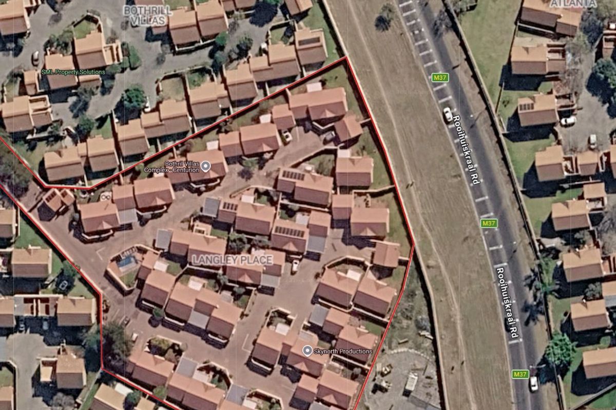 Aerial view of the Langley Place townhouse complex, showing the layout of residential units, paved access roads, and surrounding infrastructure.