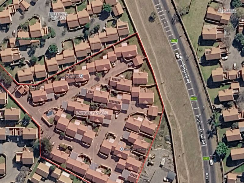 Aerial view of the Langley Place townhouse complex, showing the layout of residential units, paved access roads, and surrounding infrastructure.
